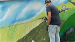 L'artista Karim Cherif dipinge il muro del parco giochi Don Rubino di La Morra